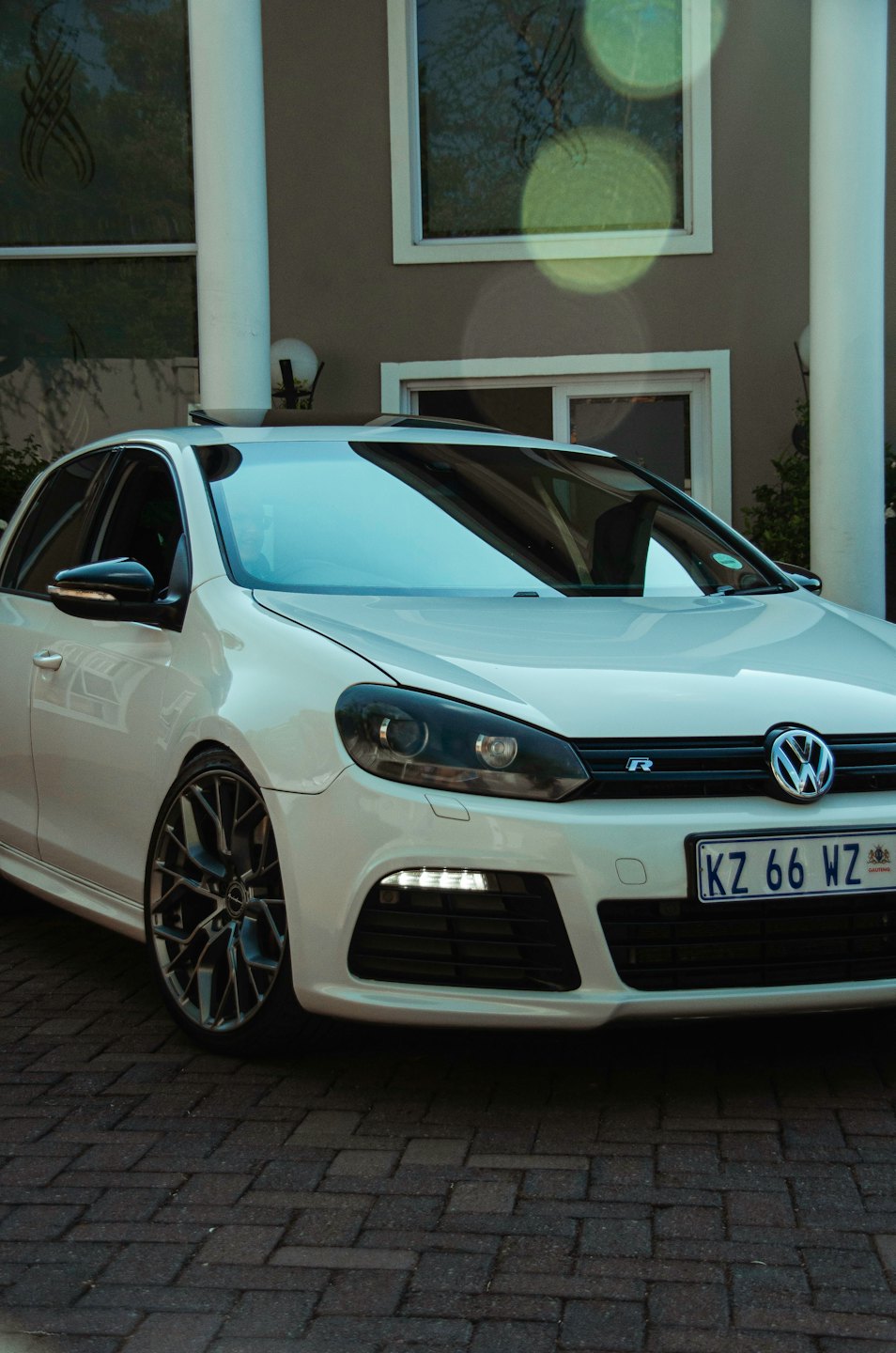 A white sports car parked in a modern home driveway.