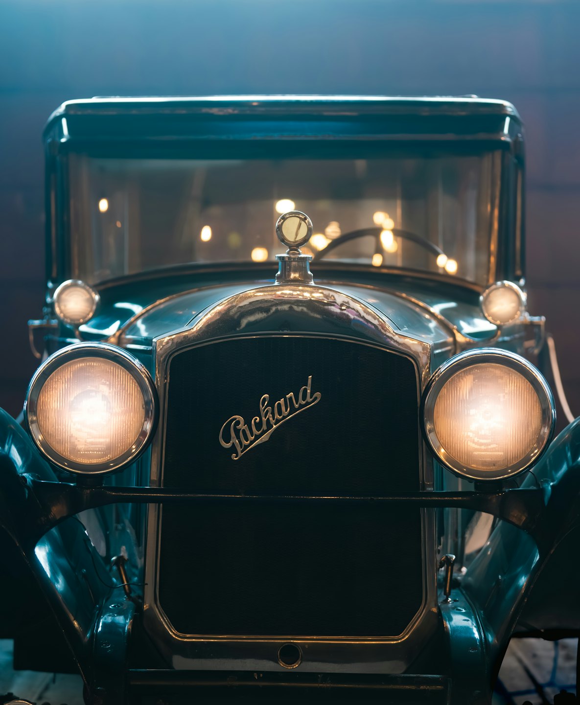 Vintage car with illuminated headlights and chrome grille.