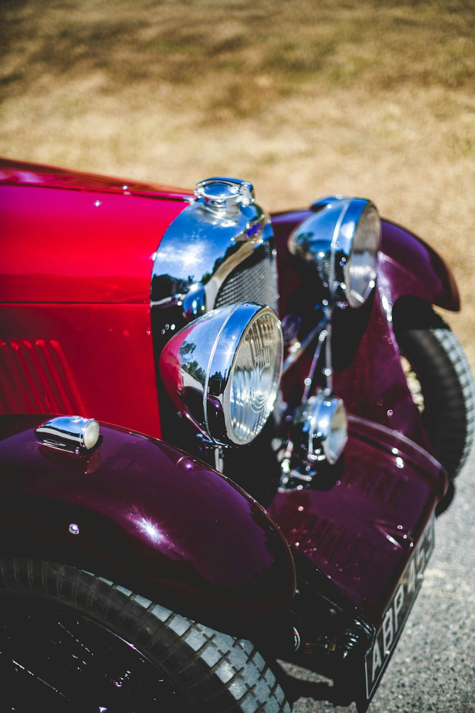 Front view of a shiny red and maroon vintage car.