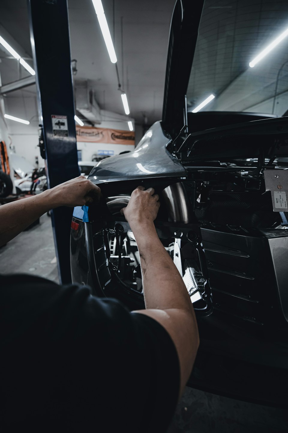 Mechanic's hands working on a car's rear panel.